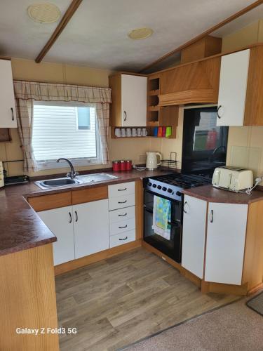 a kitchen with white cabinets and a stove top oven at Home from home in Little Holland