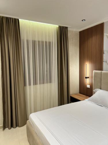 a bedroom with a white bed and a window at Kamberi Hotel & Apartments in Velipojë