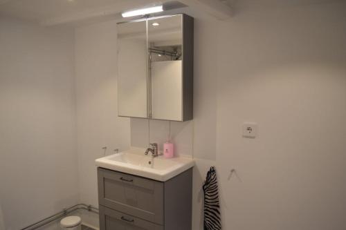 a white kitchen with a sink and a mirror at Litet mysigt hus i Östra Göinge in Västraby