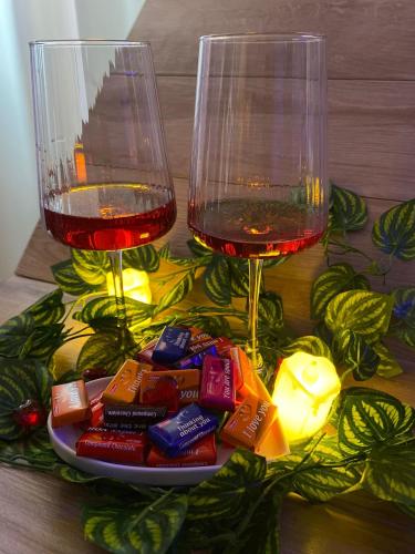 two wine glasses sitting next to a plate of candy at Prenoćište SILVER LUX Srebrno Jezero 10 in Veliko Gradište