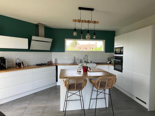 une cuisine avec des armoires blanches et des murs verts dans l'établissement Chambres 9min circuit du mans, à Voivres-lès-le-Mans