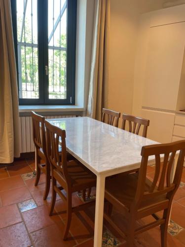 a dining room table with wooden chairs and a white table at Villa liberty sui navigli in Corsico