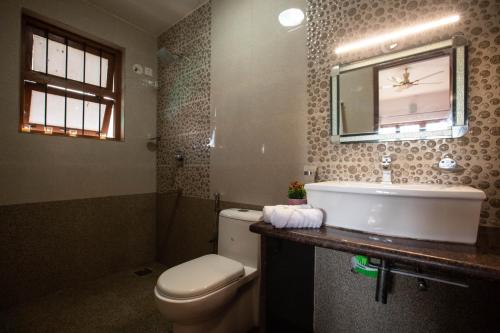 a bathroom with a toilet and a sink and a mirror at Thor Villa, 5BHK-Private Pool-Cook-Caretaker in Assagao