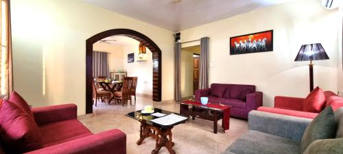 a living room with purple couches and a table at Thor Villa, 5BHK-Private Pool-Cook-Caretaker in Assagao