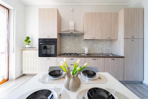 a kitchen with a table with a vase of flowers on it at Elegante Appartamento con Terrazzo - Parcheggio Gratuito Privato & Wifi in Borgo San Dalmazzo