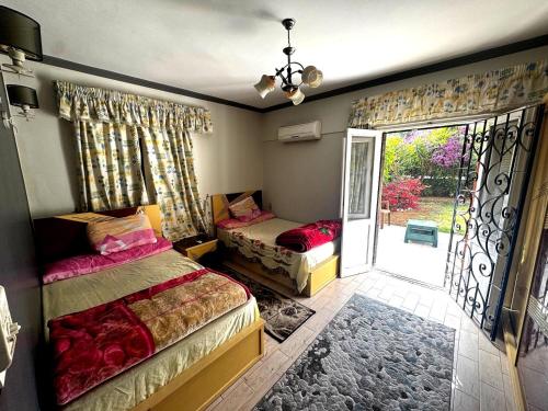 a bedroom with two beds and a sliding glass door at شقة غرفتين نوم بحديقة خاصة في المعمورة الشاطئ دور أرضي in Alexandria