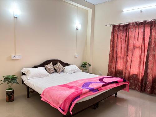 a bedroom with a large bed with a red curtain at Homely Hideout in Pālampur