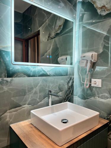 a bathroom with a white sink and a mirror at Kamberi Hotel & Apartments in Velipojë