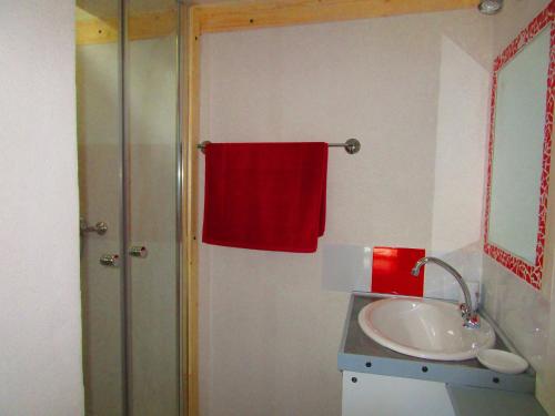 une salle de bain avec un lavabo et une serviette rouge dans l'établissement Eco maisonnette, à Sulniac