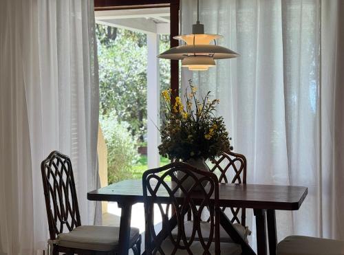 a dining room table with chairs and a vase of flowers at Cala dei Pirati in Punta Ala