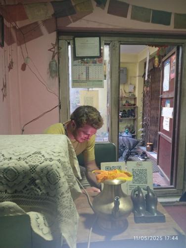 a woman in a room with a table with a plate of food at Everest Home Stay Temal Kalimati Tower in Thapathali