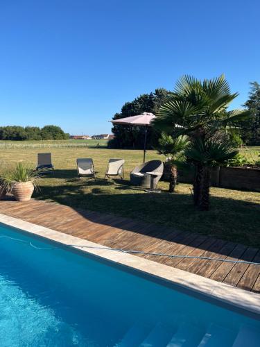 une piscine avec deux chaises et un parasol dans l'établissement Petite dépendance vue piscine, à Oisly