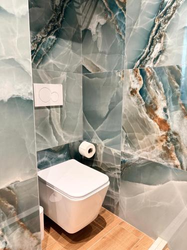 a bathroom with a toilet and a marble wall at Kamberi Hotel & Apartments in Velipojë