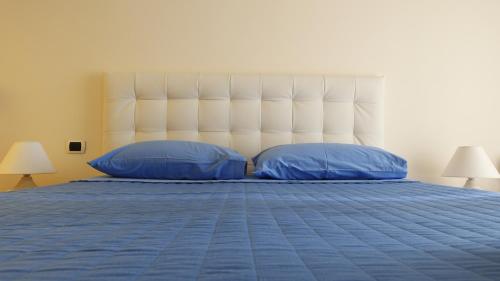 a bed with two blue pillows and a large headboard at The Cozy Place in Bari Palese
