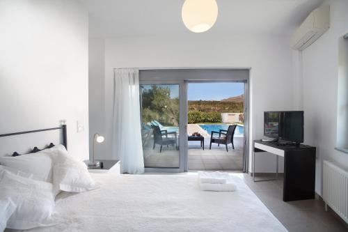 a bedroom with a bed and a television and a patio at Gramvousa Villas in Kissamos