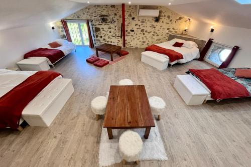 Cette grande chambre comprend deux lits et une table. dans l'établissement La Grange de Lucien - Meyras, à Meyras