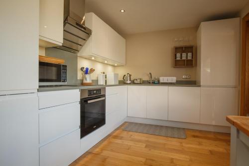 a kitchen with white cabinets and a wooden floor at Roxy's Place in Portballintrae