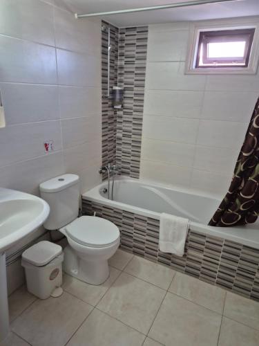 a bathroom with a toilet and a tub and a sink at Myriama Apartments in Ayia Napa