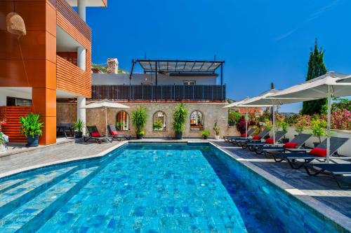 a swimming pool with chairs and a building at Lupia Suites in Kalkan