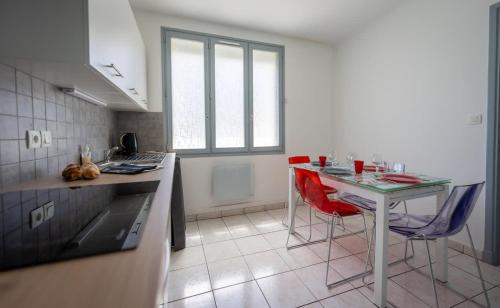 - une cuisine avec une table et des chaises rouges dans l'établissement Logement Vacances La Rochelle, à Aytré