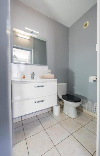 une salle de bain avec un lavabo blanc et des toilettes dans l'établissement Logement Vacances La Rochelle, à Aytré