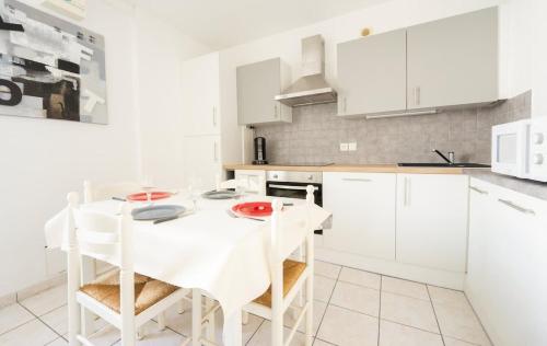 a white kitchen with a white table and white cabinets at Appart' des Tours de La Rochelle in Aytré