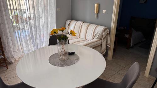 a white table with a vase with yellow flowers on it at Το Φιλόξενο Σπιτάκι! - The Friendly Nest ! in Paralion astros