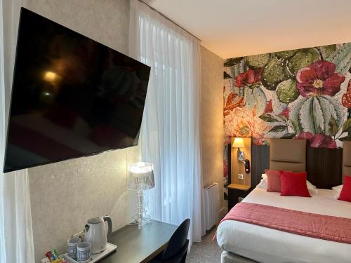 a hotel room with a bed and a tv on the wall at HOTEL ARVERNA VICHY - ClT'HOTEL in Vichy