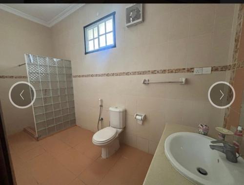 a bathroom with a toilet and a sink and a window at Villa Zara in Zanzibar City