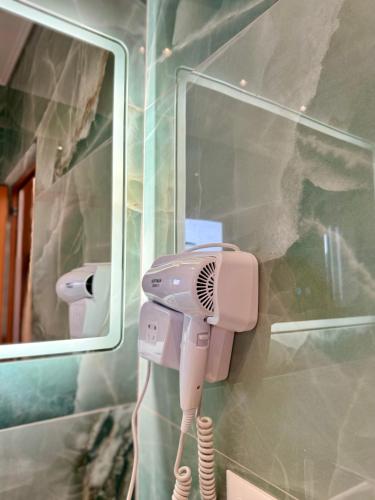 a pink hair dryer in front of a mirror at Kamberi Hotel & Apartments in Velipojë