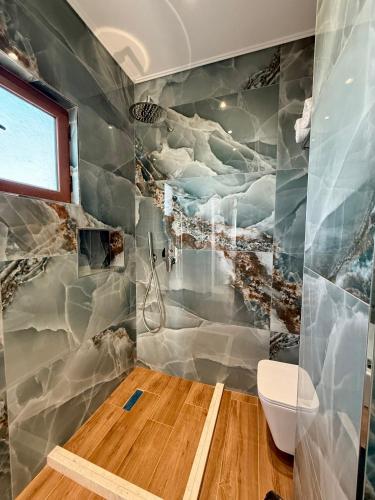 a bathroom with a shower with a painting on the wall at Kamberi Hotel & Apartments in Velipojë