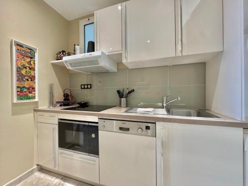 une cuisine avec des armoires blanches et un évier dans l'établissement 1-bedroom apartment with balcony and sea view on La Croisette, à Cannes