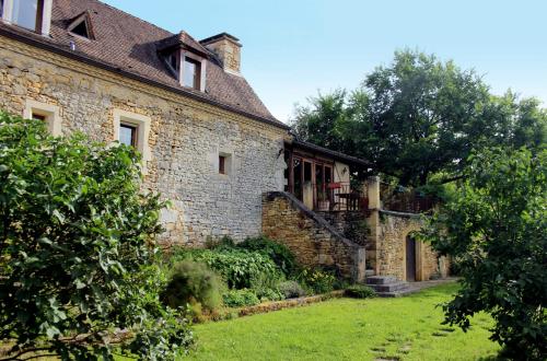 une ancienne maison en pierre avec une cour herbeuse dans l'établissement Domaine du Fraysse L'Ermitage un coin de paradis, à Saint-Cybranet