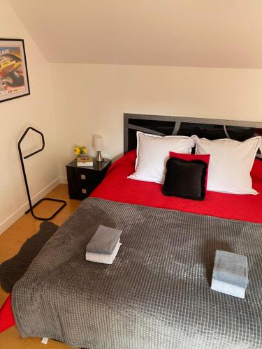 Cette chambre comprend un grand lit avec des draps rouges et des oreillers blancs. dans l'établissement LES JARDINS DE MA-MANS Maison cosy centre Le Mans PARKING privé gratuit, au Mans