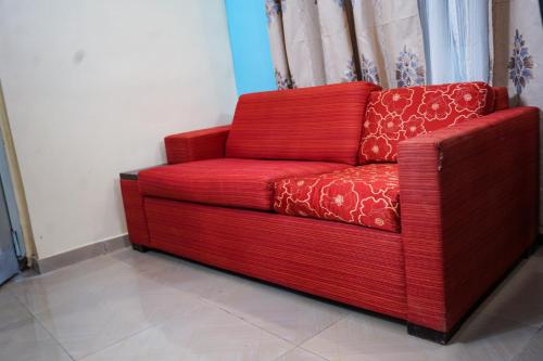 a red couch sitting in a room next to a window at EKA ELITE HOTEL in Lomé