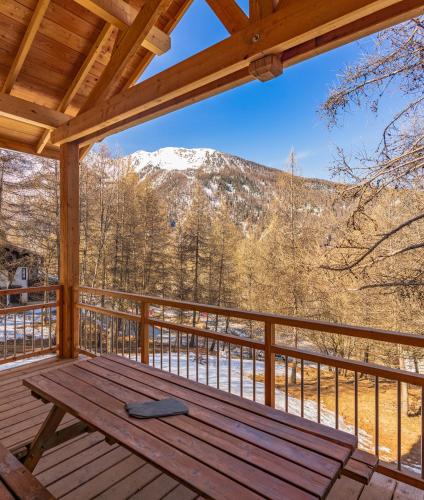 un porche en bois avec une table de pique-nique sur une terrasse avec une montagne dans l'établissement Chalet du Trappeur, aux Orres