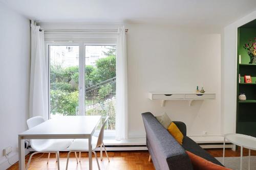 un salon avec un canapé, une table et une fenêtre dans l'établissement Studio Dumas - Charonne by B'Your Home, à Paris