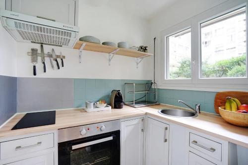une cuisine avec des armoires blanches, un évier et une fenêtre dans l'établissement Studio Dumas - Charonne by B'Your Home, à Paris