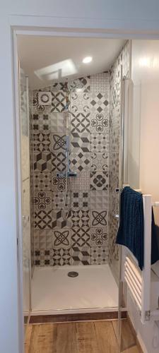 La salle de bains est pourvue d'une douche et d'un mur en carrelage. dans l'établissement La Sardinière, Charmante maison dans un jardin, à Château-Renault