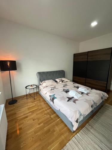 a bedroom with a large bed and a lamp at Golden Royal SM in Kragujevac