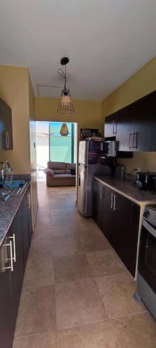 une cuisine avec des appareils en acier inoxydable et un salon dans l'établissement Villa acogedora en urb cerca del Malecon Salinas, à Salinas