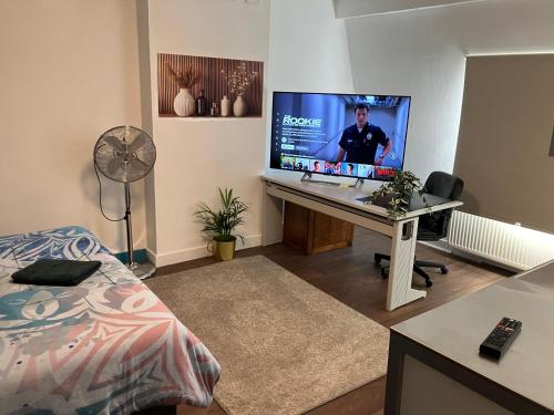 a room with a desk with a large monitor on it at Gaby's House in Liège