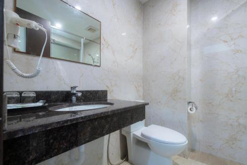 a bathroom with a toilet and a sink and a mirror at COCO Tuan Chau Hotel in Ha Long