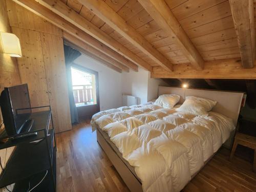 duże łóżko w pokoju z drewnianym sufitem w obiekcie Superbe T4 mansardé - 3 chambres - Vue panoramique - Parking privé - FR-1-629-112 w mieście Samoëns