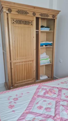 a bedroom with a wooden cabinet and a bed at Apartement near the Airport and beach Gzenaya in Gzennaïa