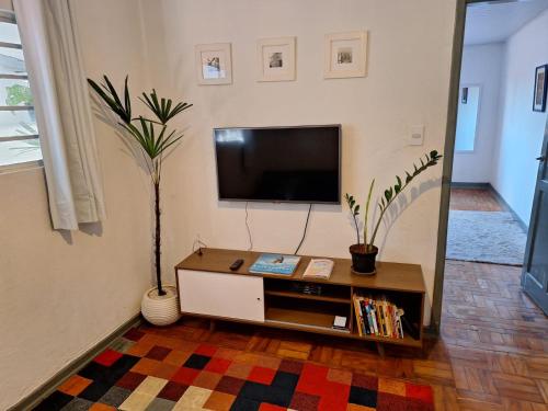 ein Wohnzimmer mit Fernseher und Tisch in der Unterkunft Casinha na Vila Madalena in São Paulo