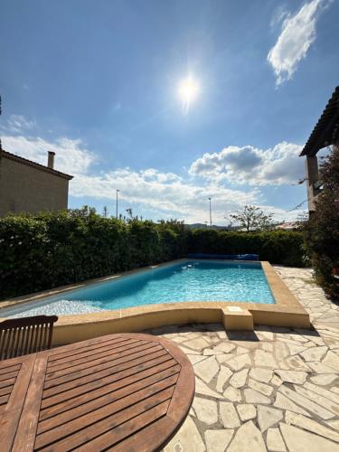 une grande piscine avec une table en bois dans l'établissement La Villa de La Ciotat, à La Ciotat