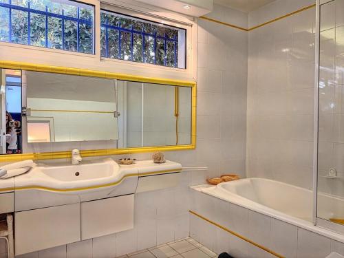 une salle de bain avec une baignoire, un lavabo et un miroir dans l'établissement Casa Blue Cala Rossa with Pool, à Lecci