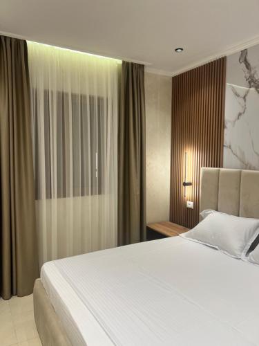 a bedroom with a large white bed and a window at Kamberi Hotel & Apartments in Velipojë