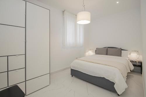 a white bedroom with a bed and a dresser at NEW! Stunning modern 2BR apt next to Feria in Seville